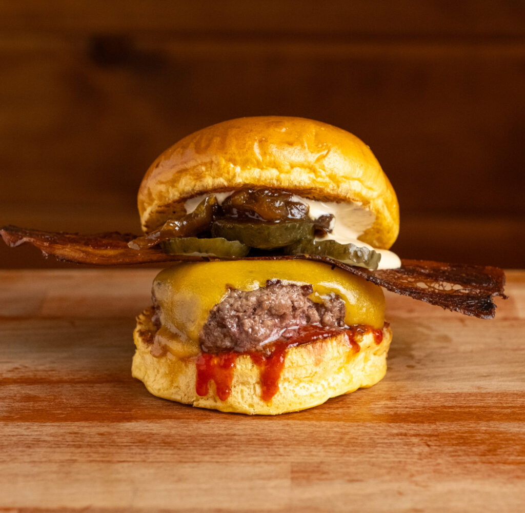 Hamburguesa con cheddar, bacon, cebolla caramelizada, pepinillos y salsa ligeramente picante