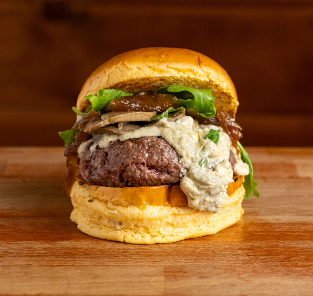 Hamburguesa con queso azul, champiñones al ajillo, cebolla caramelizada y rúcula
