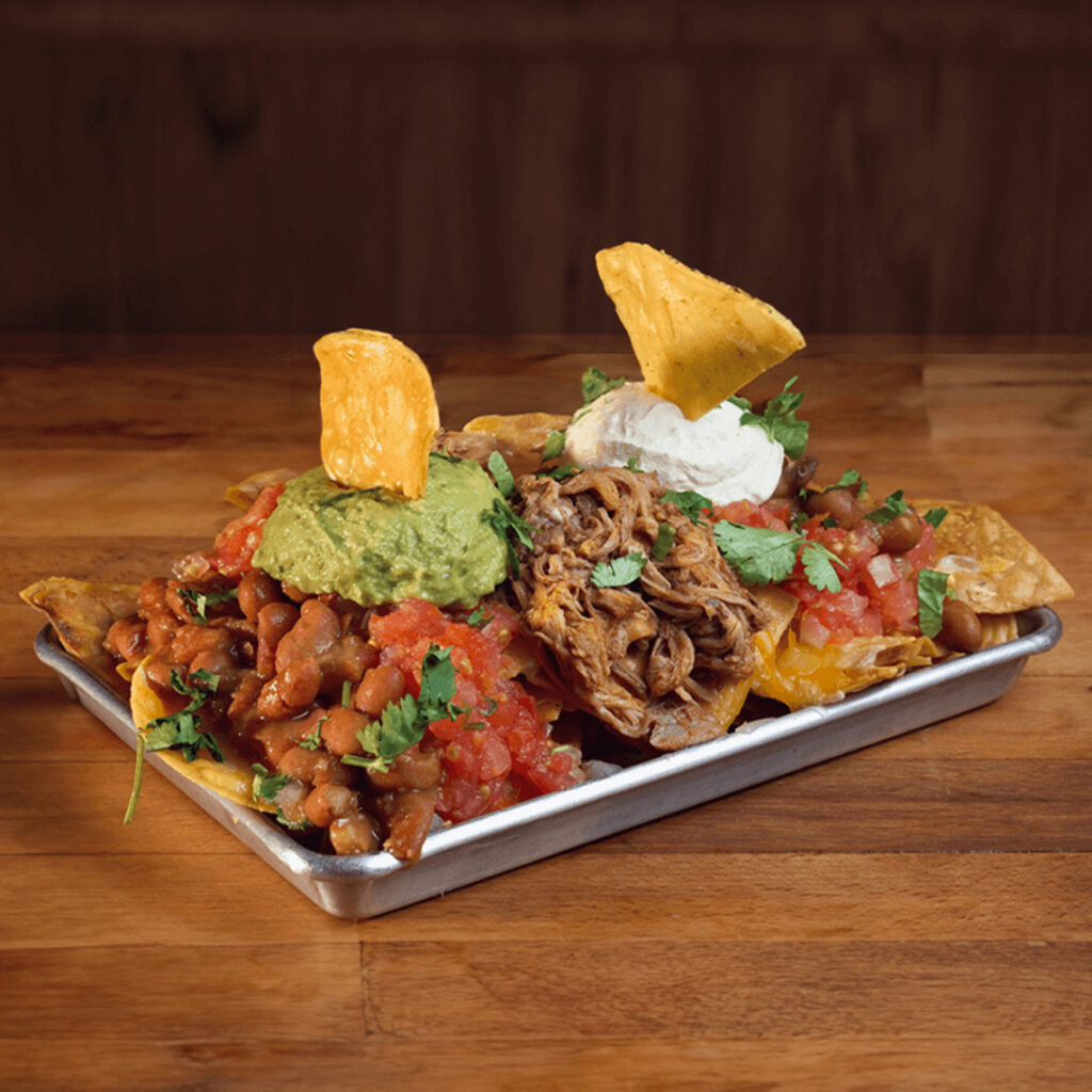 Nachos con Smoked Pulled Pork, frijoles, guacamole, pico de gallo y crema agria y queso gratinado en Madrid