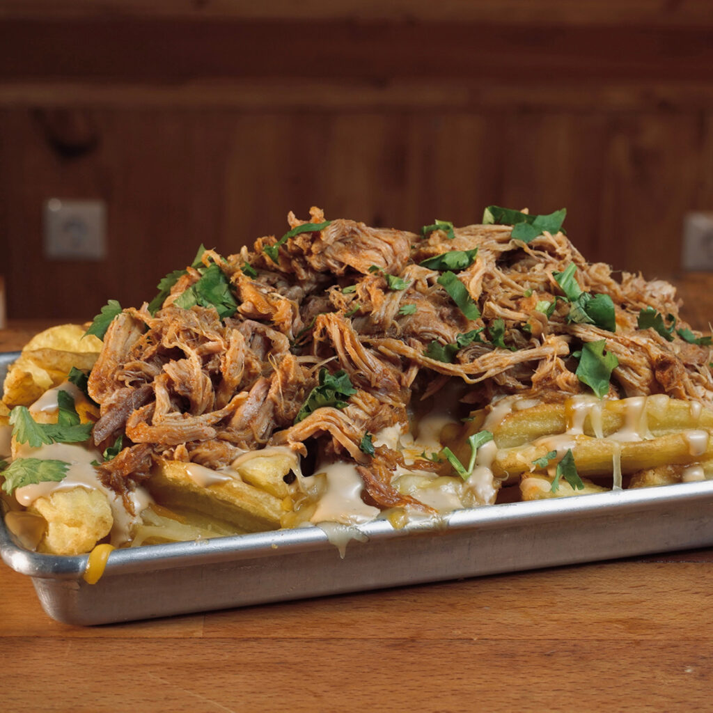 Patatas rústicas con Smoked Pulled Pork, mix de quesos americanos, mayonesa especial y lluvia de cilantro con salsa bbq en Madrid